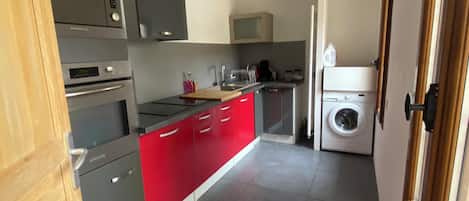 A modern kitchen with grey and red cabinetry, stainless steel appliances, and a built-in washing machine.
