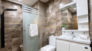 Une salle de bain moderne avec une douche à parois de verre, un lavabo blanc et un grand miroir au-dessus du meuble-lavabo.