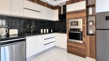 Eine moderne Küche mit Edelstahlgeräten, einer schwarzen Granitabdeckung und Holzschränken.
