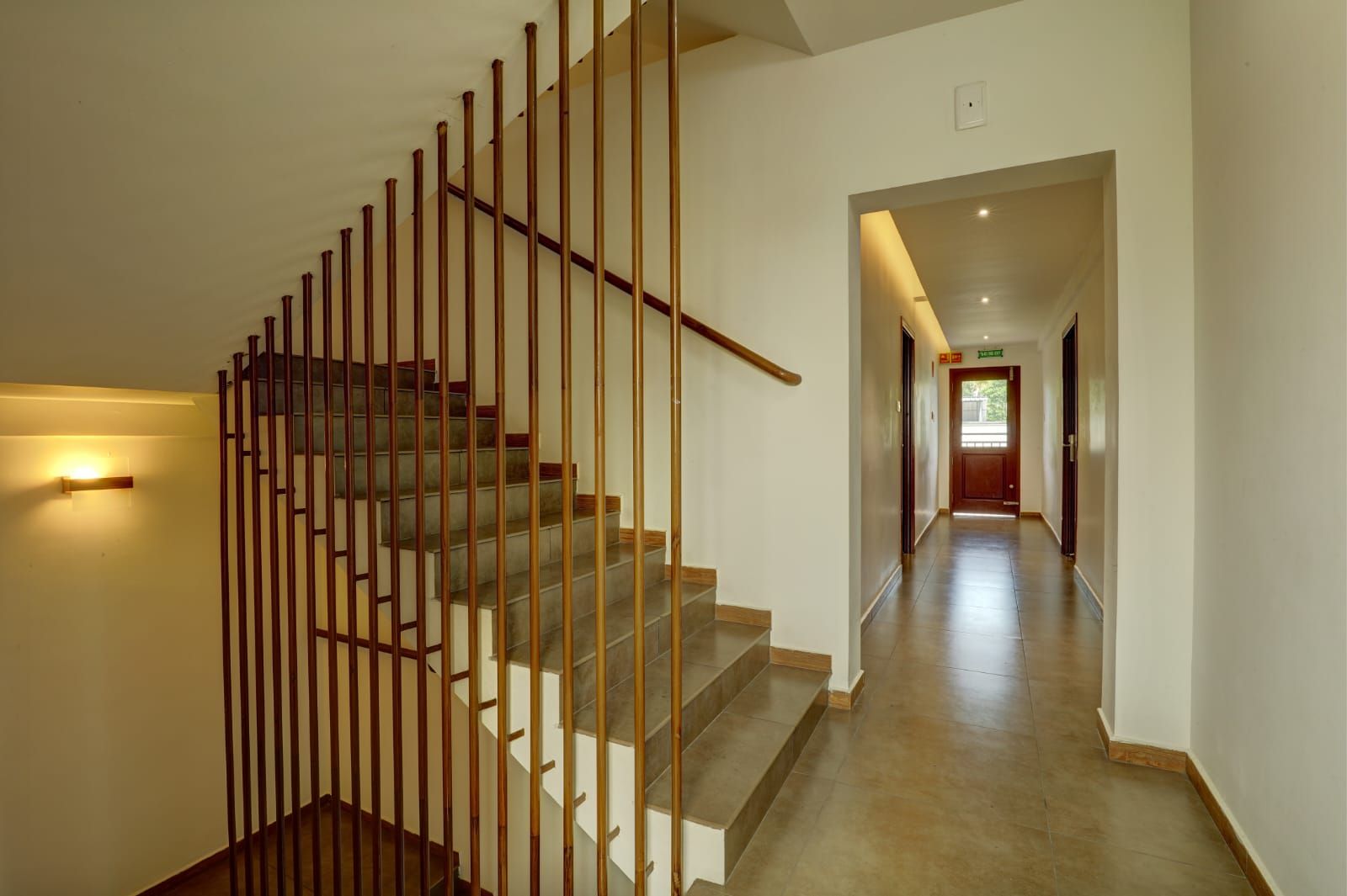 A staircase with a wooden handrail and a light fixture on the wall.