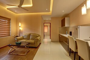A modern living room with a sofa, a coffee table, and a ceiling fan. - Hotel JP Park-near Rajagiri Hospital (Aluva)