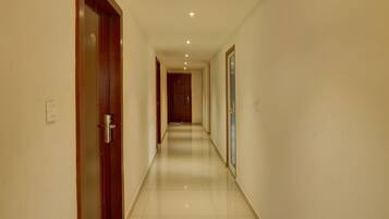 Un pasillo largo y estrecho con una puerta de madera a la izquierda y una ventana a la derecha.
