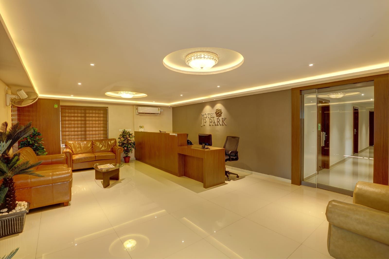 A hotel reception area with a reception desk, seating area, and a glass partition.