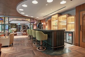 Eine moderne Bar mit einer Theke, Hockern und einem mit Getränken gefüllten Kühlschrank.