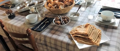 A breakfast table set with various dishes, including bread, fruits, and a newspaper.