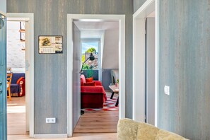 A hallway with a red sofa, a patterned rug, and a wall-mounted calendar. - Apartment 'Fewo-basche' with Balcony and Wi-Fi (Barsinghausen)