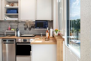 A modern kitchen with stainless steel appliances, a microwave, and a window offering a view of the outdoors. - Apartment 'Fewo-basche' with Balcony and Wi-Fi (Barsinghausen)