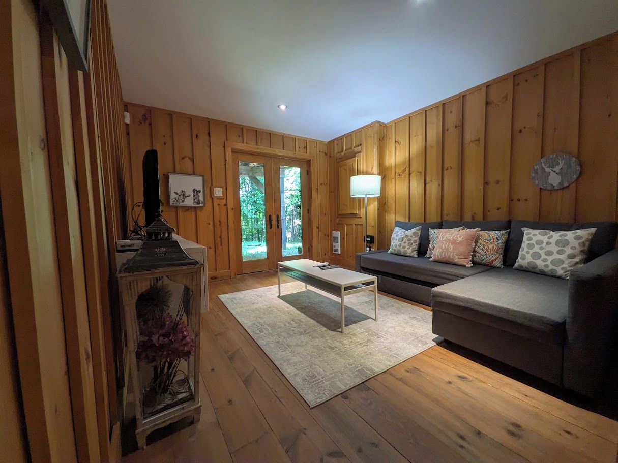 Une pièce aux murs lambrissés, avec un canapé, une table et une lampe.