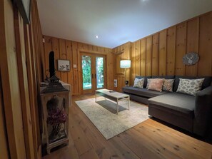 A wooden-paneled room with a sofa, a table, and a lamp. - Luxurious Cozy Getaway with great skiing, outdoor activities, hot tub, EVR. (Lac-Supérieur)