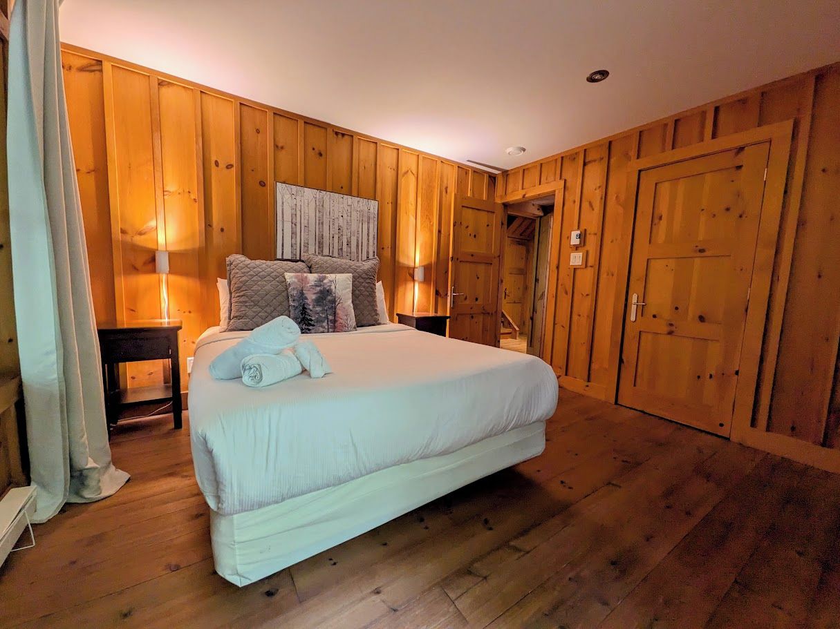 A bedroom with a large bed, wooden walls, and a wooden floor.