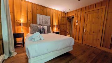 A bedroom with a large bed, wooden walls, and a wooden floor.