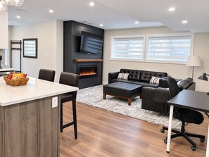 A modern living room with a fireplace, a sofa, a coffee table, and a dining area.