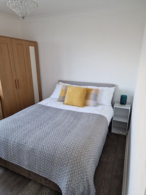 A bedroom with a bed, a wardrobe, and a bedside table.