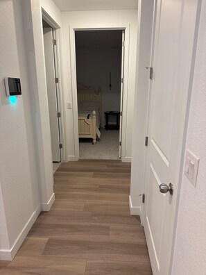 A hallway leading to a bedroom with a bed, bedside table, and a wall-mounted light fixture. - Welcoming 1-bedroom house with AC in charming Littleton (Littleton)
