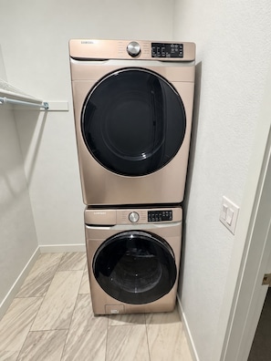 A wall-mounted washer and dryer unit in a corner with a light-colored floor. - Welcoming 1-bedroom house with AC in charming Littleton (Littleton)