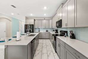 A modern kitchen with white cabinets, a marble floor, and stainless steel appliances. - Sleeps 15·Private Pool·Themed Rooms·Game Room (Kissimmee)