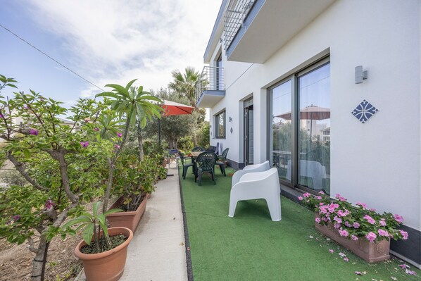 A patio with a table and chairs, potted plants, and a small garden area.