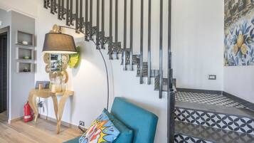 Uma sala de estar moderna com sofá, luminária e escada com ladrilhos estampados.