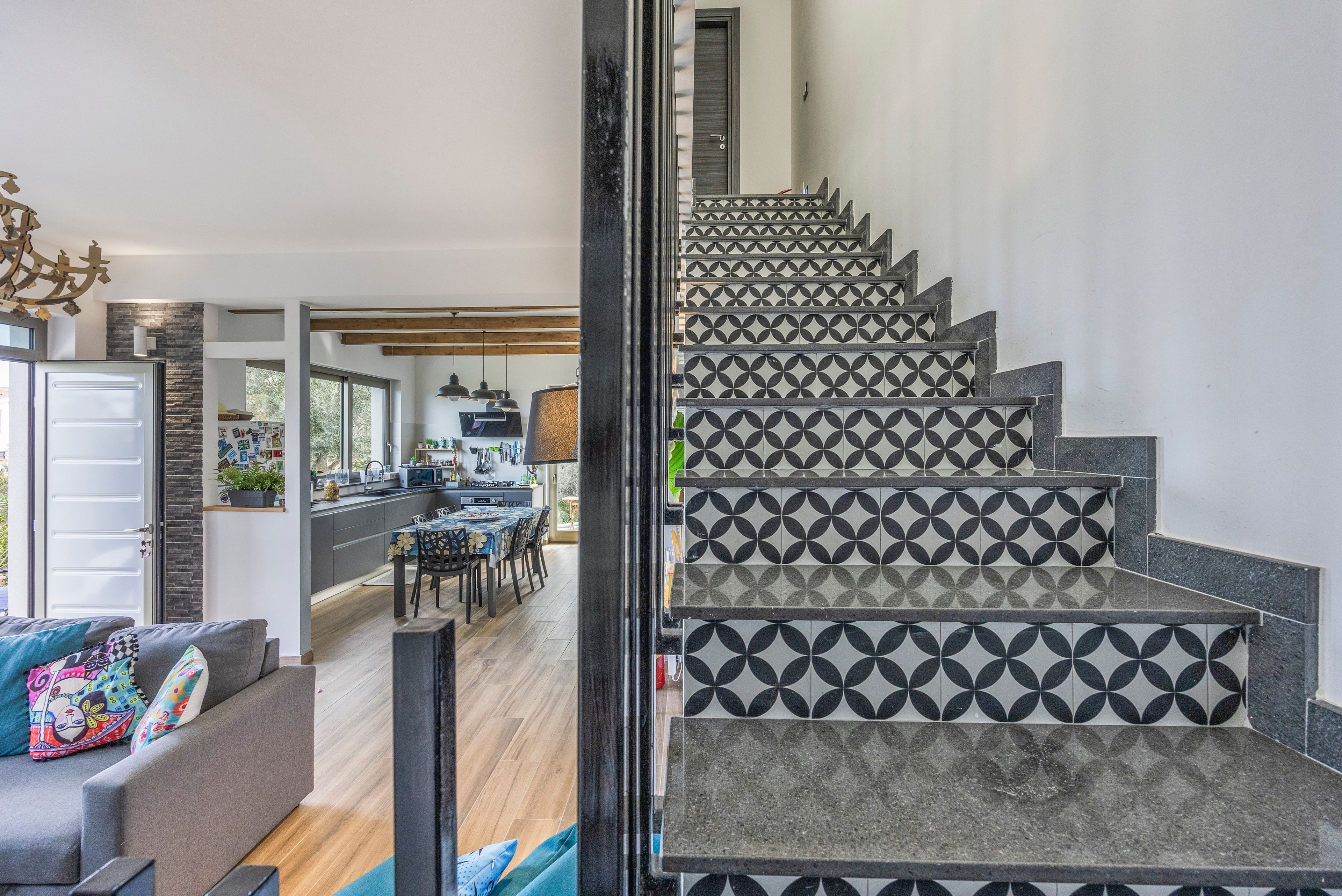 Una escalera con azulejos de diseño geométrico que conduce a un comedor con vistas al exterior.