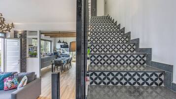 Una escalera con azulejos de diseño geométrico que conduce a un comedor con vistas al exterior.