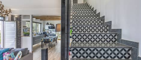 Una escalera con azulejos de diseño geométrico que conduce a un comedor con vistas al exterior.