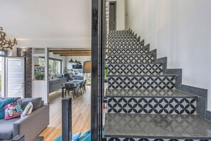 Una escalera con azulejos de diseño geométrico que conduce a un comedor con vistas al exterior.