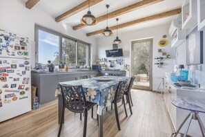 Una cocina moderna con una isla central, vigas de madera y un comedor con mantel floreado.