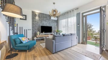 Een moderne woonkamer met een bank, een televisie en een kroonluchter.