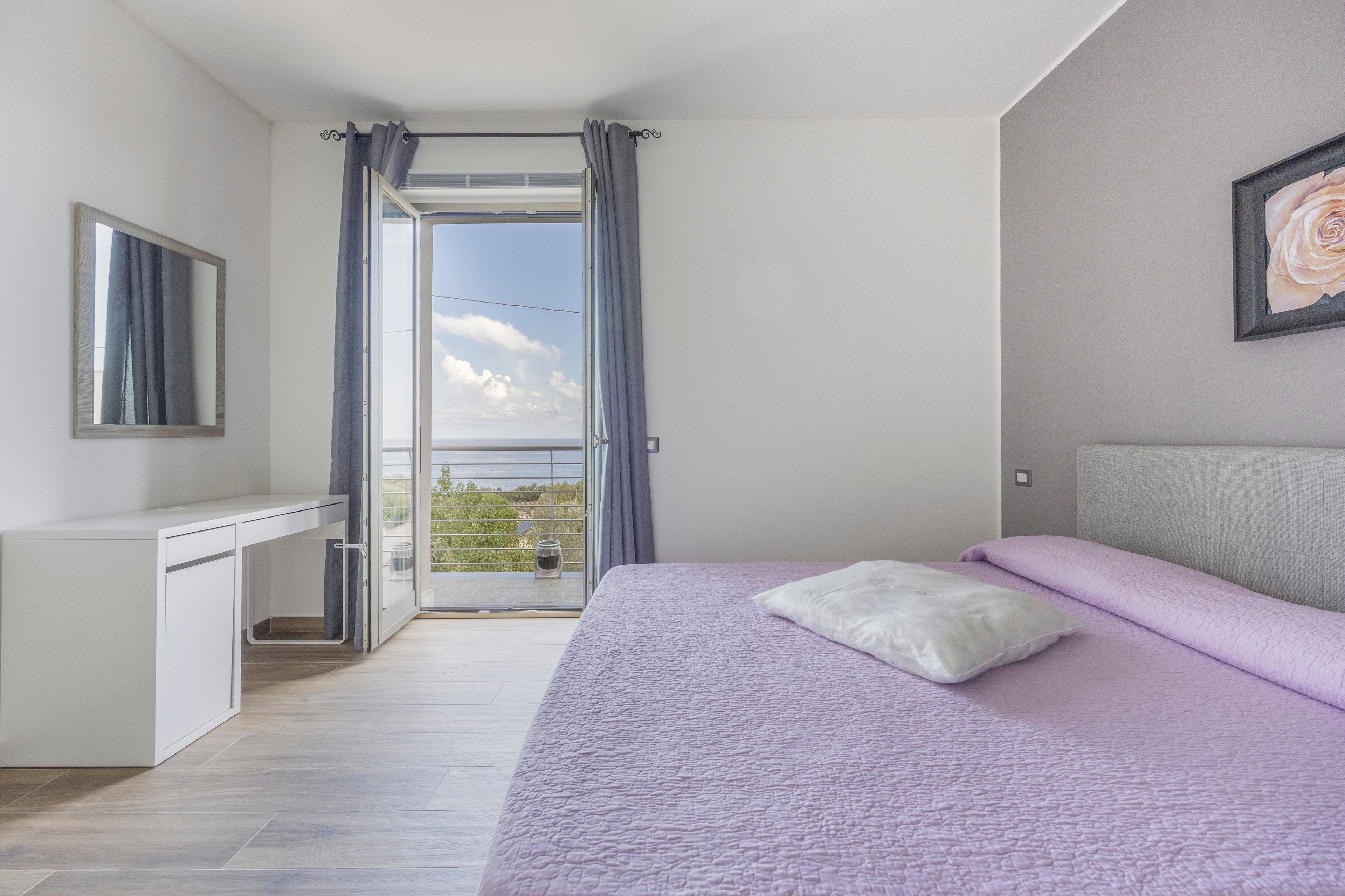 Un dormitorio con cama, escritorio y vistas a través de una puerta abierta.