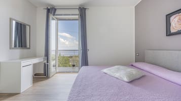 Un dormitorio con cama, escritorio y vistas a través de una puerta abierta.