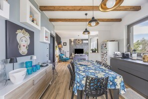 A modern kitchen with a dining area, wooden beams, and a large window.