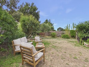 A patio with wooden furniture and a stone wall. - Beach 100m away, house for 8, garden & BBQ (Noirmoutier-en-l´Ile)