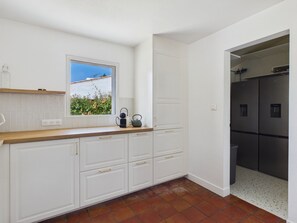 Una cocina con armarios blancos, una ventana con vistas y un refrigerador de acero inoxidable.