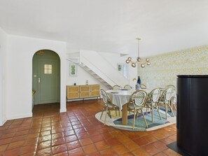 A dining area with a round table, chairs, a staircase, and a black cabinet. - Beach 100m away, house for 8, garden & BBQ (Noirmoutier-en-l´Ile)