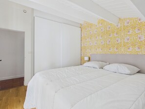 Un dormitorio con cama, armario y pared con estampado floral.