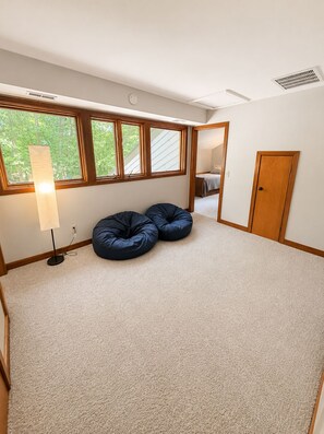 A room with a sloped ceiling, a large window, a door, and a lamp. - The Hunters Ridge Retreat (Chapel Hill)