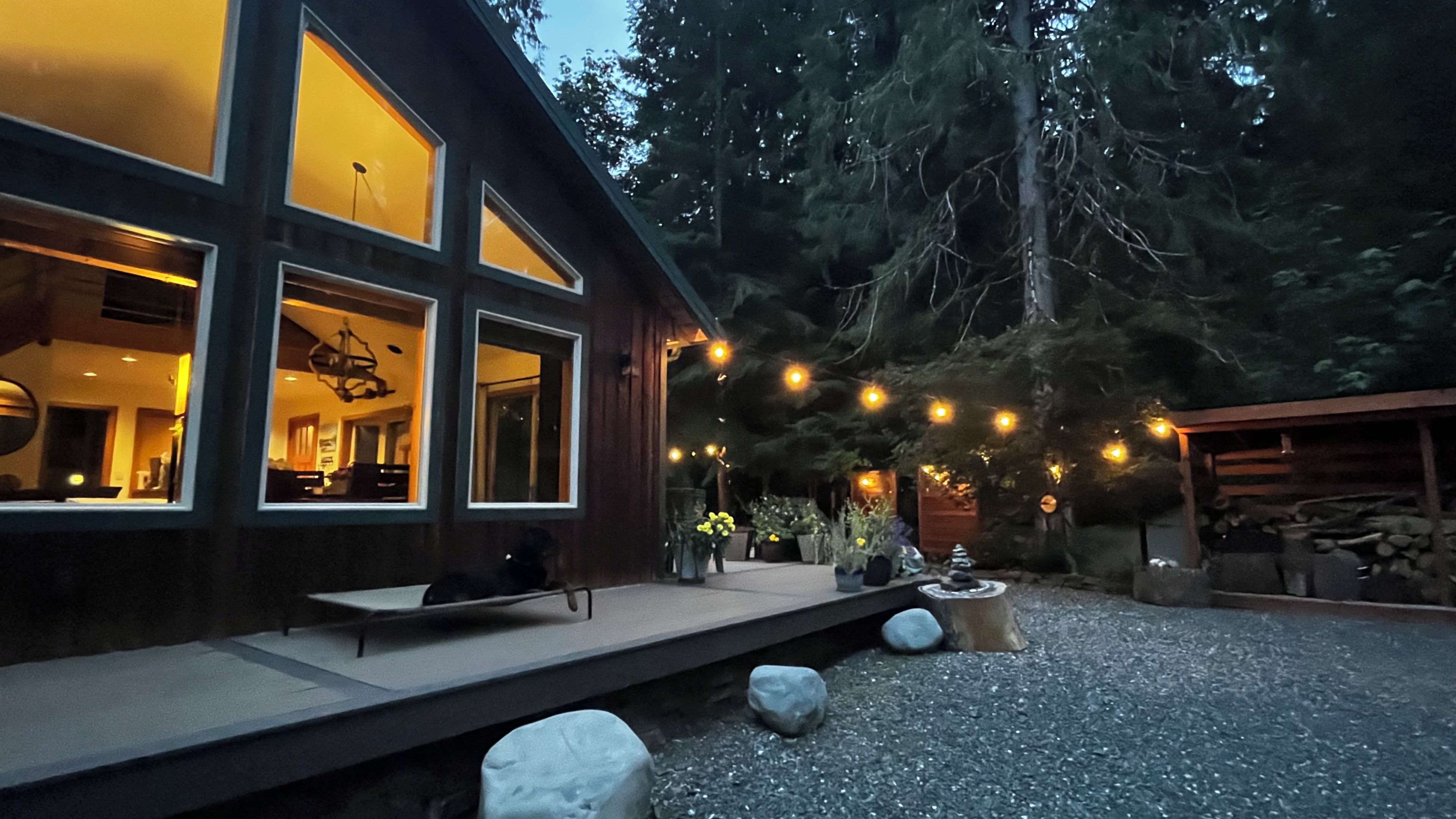A modern house with large windows, a patio, and string lights.