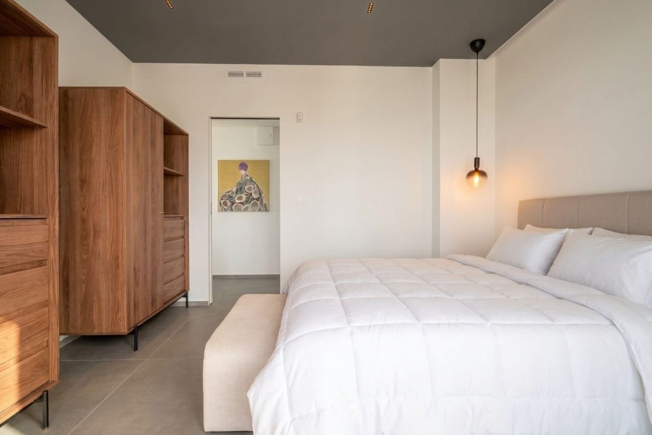 Ein Schlafzimmer mit einem großen Bett, einem Holzschrank und einem Bild an der Wand.