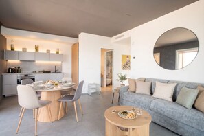 Un espace de vie moderne comprenant un coin repas, un canapé et un miroir rond.