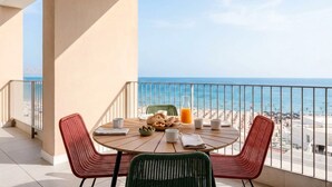 Un balcón con mesa y sillas, con vista a una playa.