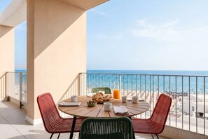 Un balcone con tavolo e sedie, vista sulla spiaggia.