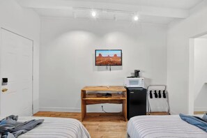 A small, compact room with two beds, a wooden desk, a microwave, and a hairdryer. - 2 Highlander Unit (Williams)