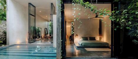A modern interior with a glass-enclosed bedroom, a pool, and a dining area with natural light.
