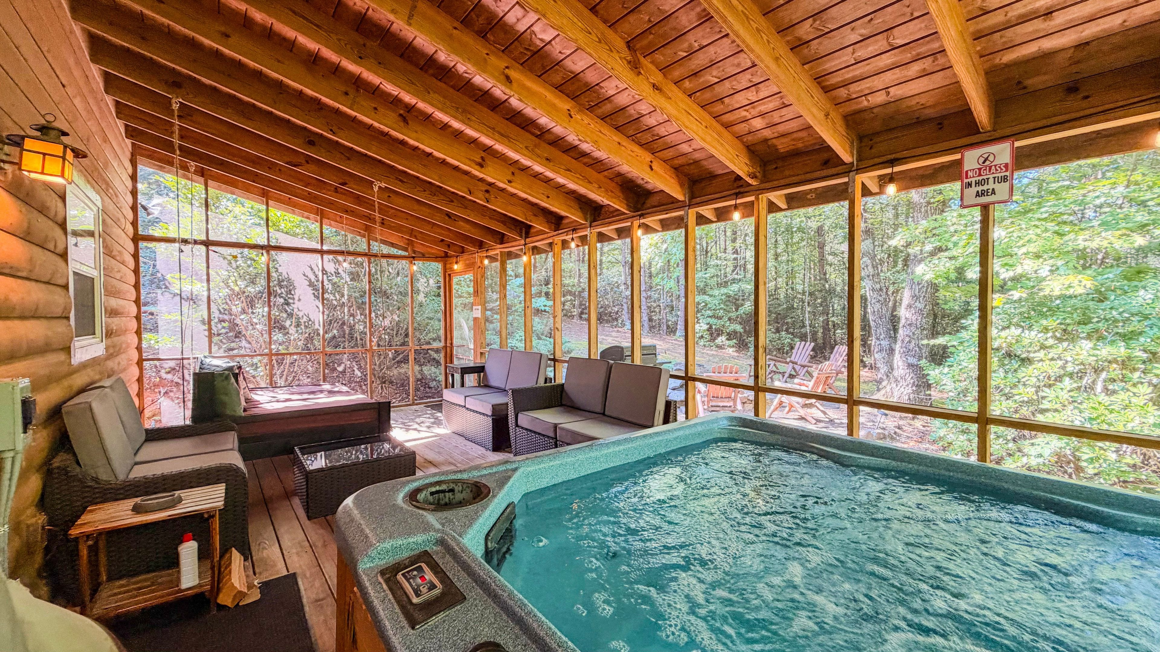 A hot tub area with wooden beams, seating, and a view of the forest.