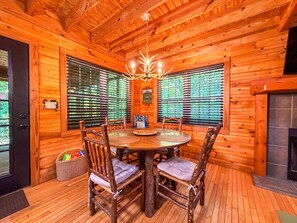 A wooden cabin interior with a round dining table, chairs, and a fireplace. - Cozy 2BR/2BA Helen Cabin for 4 | Hot Tub & Firepit (Sautee Nacoochee)