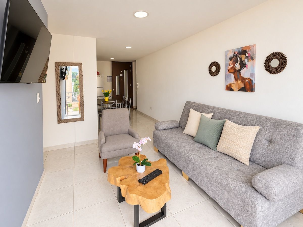 Una sala de estar moderna con un sofá gris, una mesa de centro de madera, un sillón gris y un cuadro en la pared.
