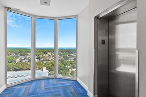 Habitació d'angle amb una finestra gran que ofereix vistes a una zona residencial i al mar.