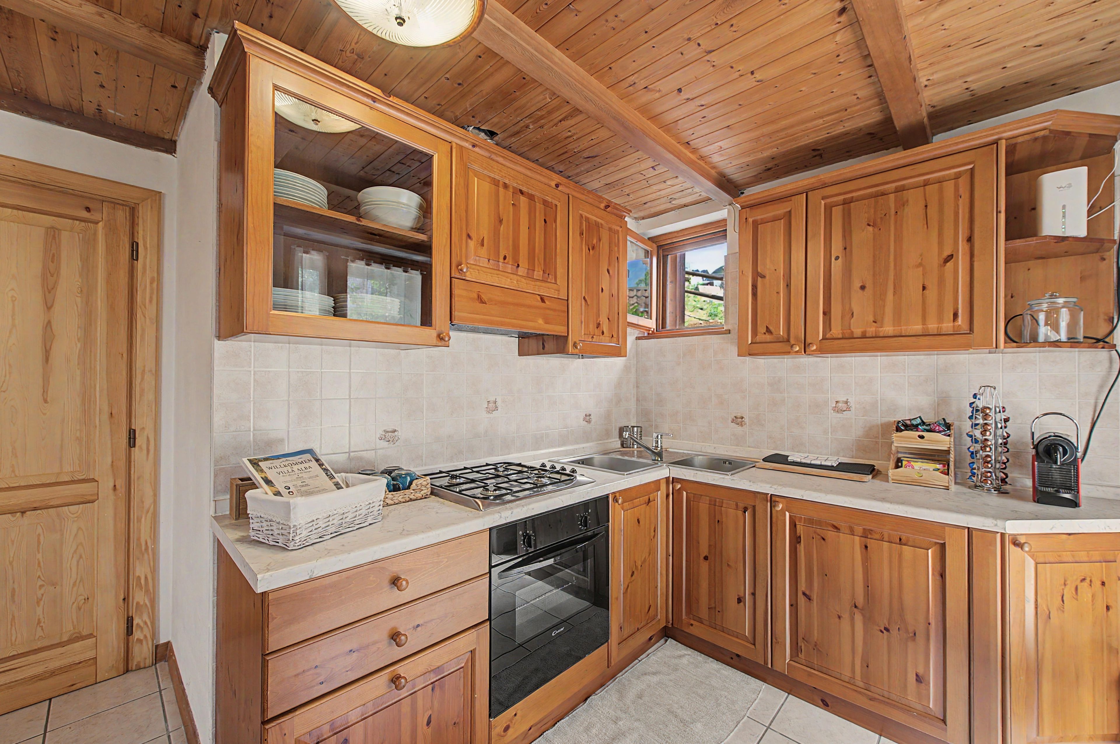 Eine Küche mit Holzschränken, einem Gasherd, einem Backofen und einem Fenster.