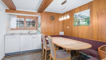 Una cocina compacta con un banco y una mesa de madera, una radio y un cuadro en la pared.