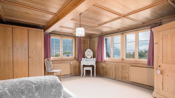 Ein Zimmer mit Holzwänden, einem Klavier, einem Sessel und einem Bett.